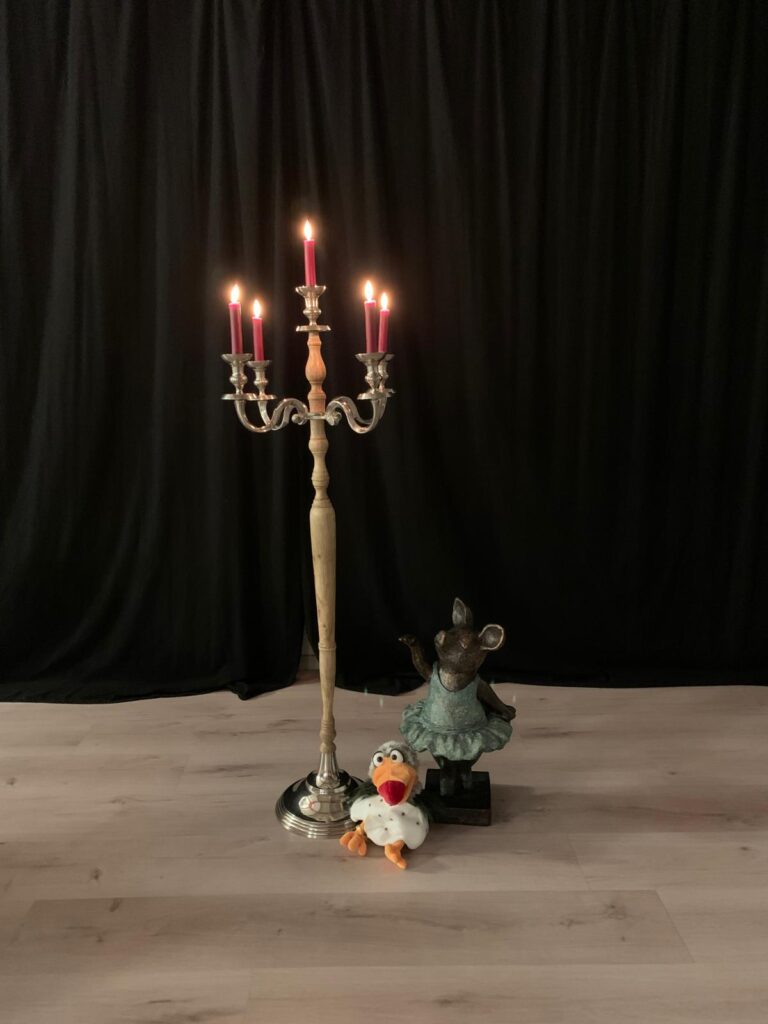 das Keks Lauenau Bild der Schweinchenfigur und einer Handpuppe neben einem Kerzenständer