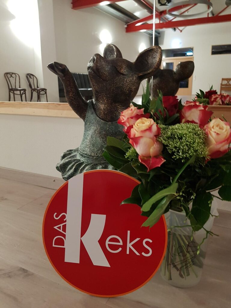 das Keks Lauenau Schweinchen Susi mit Keks Logo und Blumen